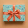 Turquoise wrapping paper with underwater-themed pattern wrapped as a gift box with a coral-red satin ribbon bow, featuring cartoon fish in various sizes and colors, spiral shells, starfish, seaweed, age number "5", and personalized "Happy Birthday Amelia" text on a neutral background.